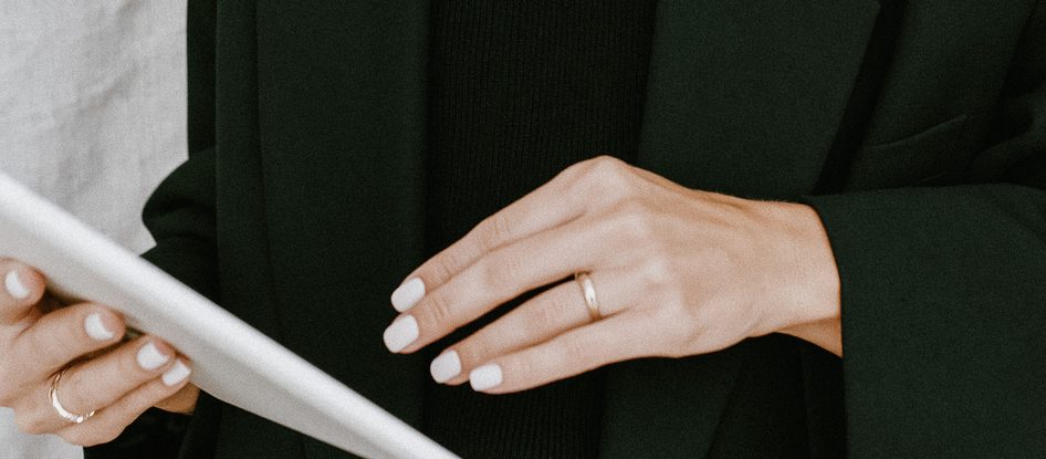 A hand in a black blazer holding the edge of a tablet.
