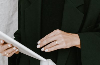 A hand in a black blazer holding the edge of a tablet.