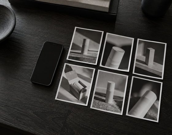Six printed product photographs laid out in a grid on a dark desk beside a phone.
