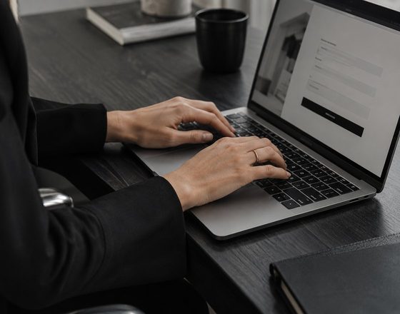 A person typing on a laptop that shows a lead capture form, on a dark desk.